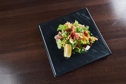 Healthy kitchen. Top view of a delicious prosciutto and arugula salad with dorblu cheese and pine nuts