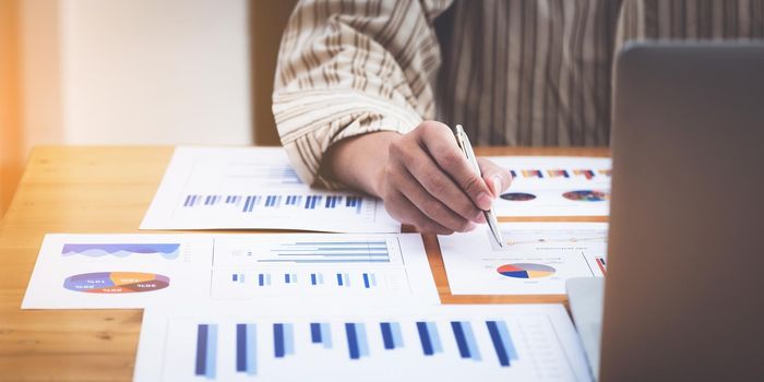 After the halfway point of the year, A fund manager examines the financial chart of marketing with paperwork