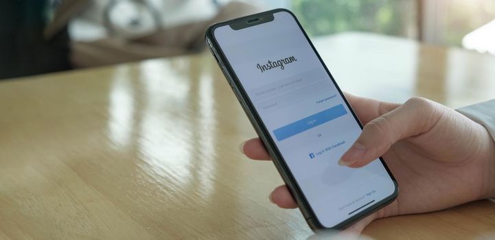 CHIANG MAI, THAILAND - OCT 4, 2020: A woman holds Apple iPhone X with Instagram application on the screen. Instagram is a photo-sharing app for smartphones..