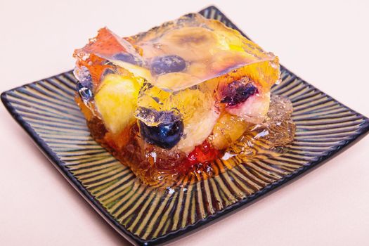 Jelly from different fruits and berries on a square saucer. Dessert. Close-up