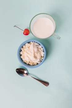 Cottage cheese in a blue bowl with sour cream and honey, a cup with milk. Morning breakfast.