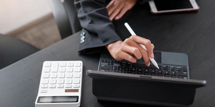 Business woman using calculator for do math finance on wooden desk in office and business working background, tax, accounting, statistics and analytic research concept.