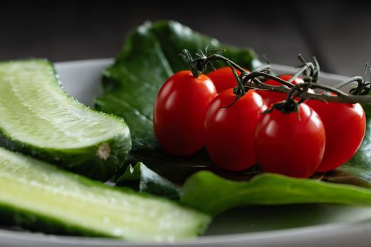 Fresh vegetables and herbs in a plate on a wooden table. Concept of vegetarianism and healthy eating.