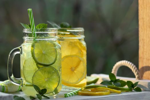 Cold refreshing homemade lemonade with mint, lemon and lime in mason jars.