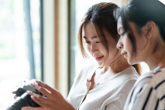 Happy charming asian women are checking and looking at their picture on the camera LCD display screen after shooting