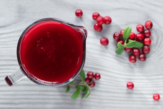 Homemade fresh wild lingonberry sauce in a glass gravy boat, top view, flat lay.