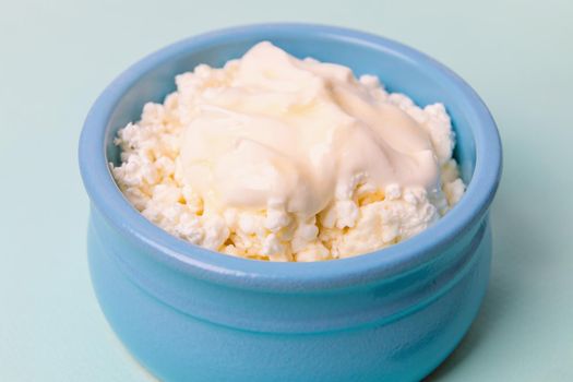 Cottage cheese in a blue bowl with sour cream and honey. Morning breakfast.