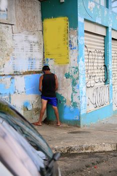 salvador, bahia, brazil - july 2, 2021: Man is seen urinating on a wall in the street in Salvador city.