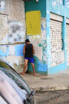 salvador, bahia, brazil - july 2, 2021: Man is seen urinating on a wall in the street in Salvador city.
