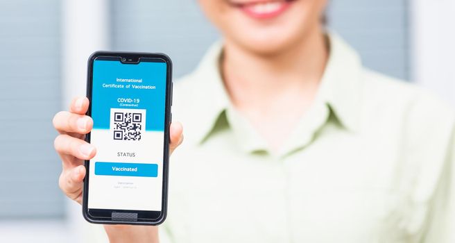 Vaccination passport, Traveler woman smiling holding health passport of vaccination certification on smartphone app at airport for travel during coronavirus pandemic, Mobile app of virus COVID-19