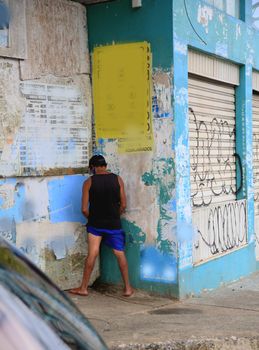 salvador, bahia, brazil - july 2, 2021: Man is seen urinating on a wall in the street in Salvador city.