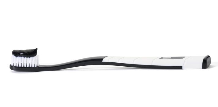 white plastic toothbrush with black charcoal paste on white background, hygitena remedy