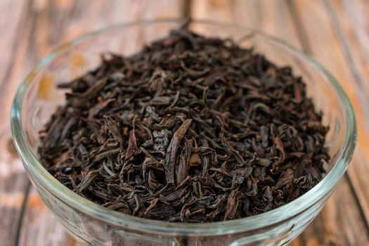 Dried large black tea leaves are poured into a glass bowl for a delicious drink