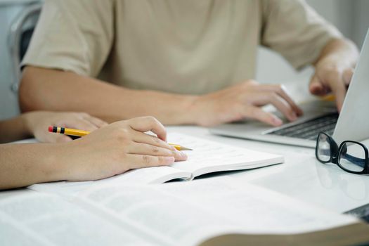 Learning, education and school concept. Young woman and man studying for a test or an exam. Tutor books with friends. Young students campus helps friend catching up and learning.