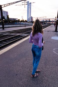 Young girl walking alone on train platform and taking photos on railway station
