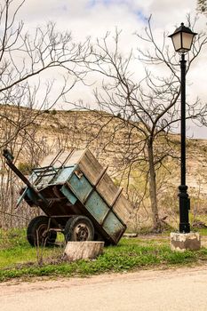 Trailer abandoned in the countryside and next to a streetlight among vegetation. Mountain in the background.