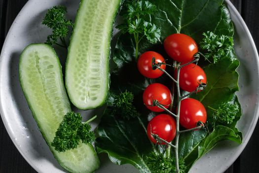 Fresh vegetables and herbs in a plate on a wooden table. Concept of vegetarianism and healthy eating.