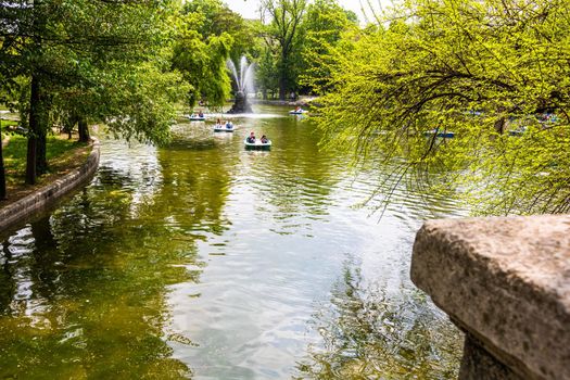 People on pedal boat on lake in Cismigiu Park, Bucharest, Romania, 2020. People walking, having fun, enjoying outdoor in park after quarantine or restrictions of coronavirus.