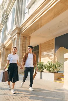 Beautiful young diverse tourist couple holding hands walking through streets in city,