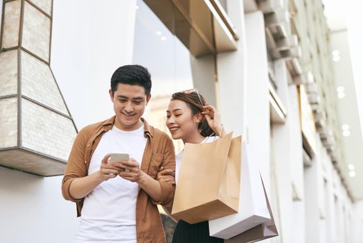 Happy beautiful couple using smart phone and shopping together.