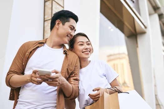 Happy beautiful couple using smart phone and shopping together.