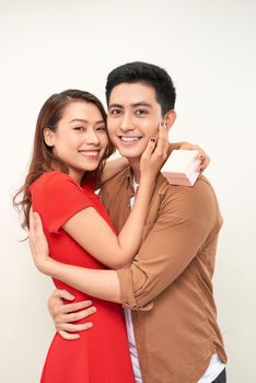 Young couple hugging with wrapped present. woman embracing man and holding present with ribbon