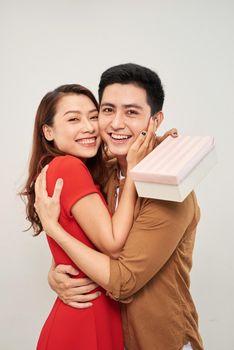 Young couple hugging with wrapped present. woman embracing man and holding present with ribbon