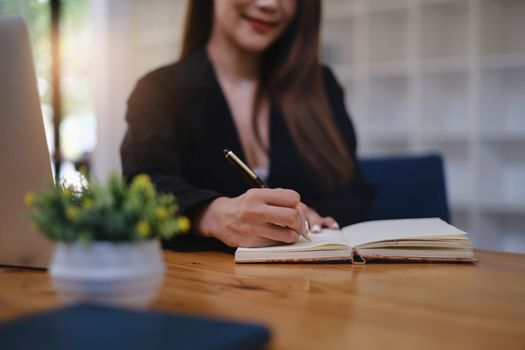 A woman studying webinar by laptop computer and taking note