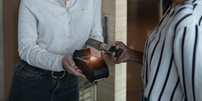 A woman paying bill by online banking application on her smartphone at shopping mall