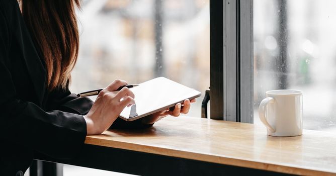 Close up business woman working with digital tablet on wooden desk with coffee morning,