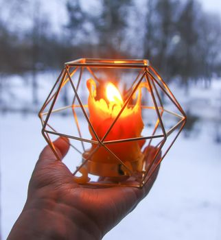 Warm light of hand made natural bee wax dying candle in a candleholder on wooden slice.