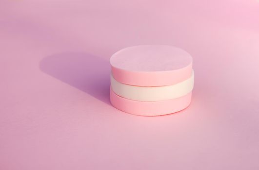 Cosmetic sponges in pastel colors on soft pink background.