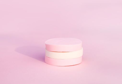 Cosmetic sponges in pastel colors on soft pink background.
