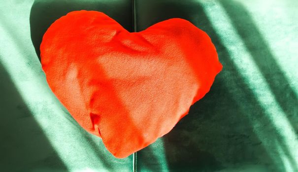 Heart shaped small decorative pillow on soft green pouffe. Modern interior cozy design element