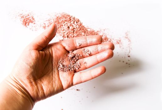 Sample of dry shiny highlighter particles scattered on a white background and stained female fingers