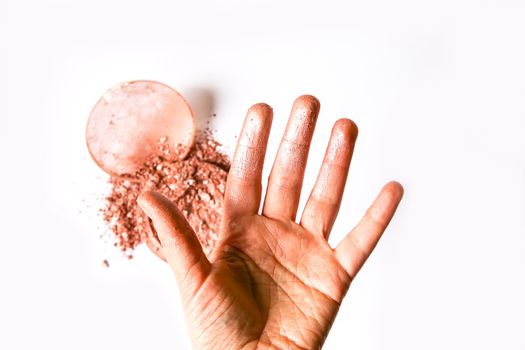 Sample of dry shiny highlighter particles scattered on a white background and stained female fingers