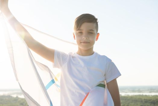 BARNAUL CITY. RUSSIA - JUNE 08, 2021: Portrait of boy waving flag the Olympic Games outdoors over cloudy sunset sky. Children sports fan. Summer olympic games concept on June 08, 2021 in Altayskiy krai, Siberia, Barnaul, Russia