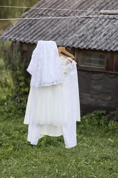Linen dresses hanging on a wooden hangers outdoors in summer day