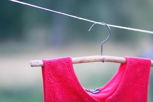 Linen red dress hanging on a hanger outdoors in summer day