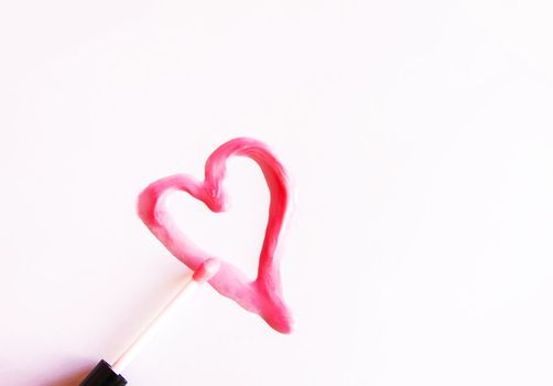 Heart drawn sample of pink lip gloss on a white background.