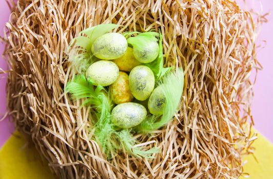 Easter composition with traditional decor. Small decorative colorful eggs on soft artificial hay.