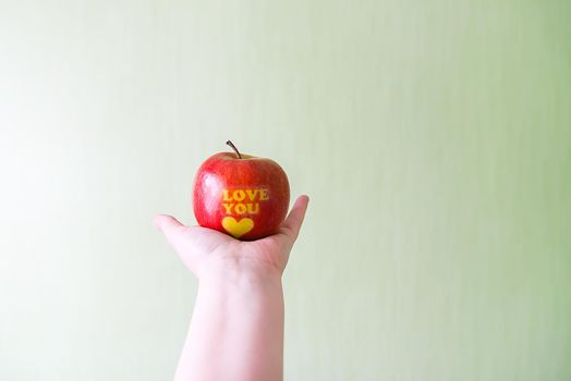 Fresh red apple in hand with words I love you and heart.