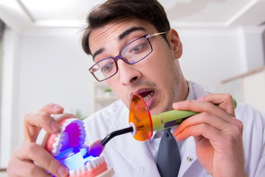 Funny dentist with curing light in medical concept