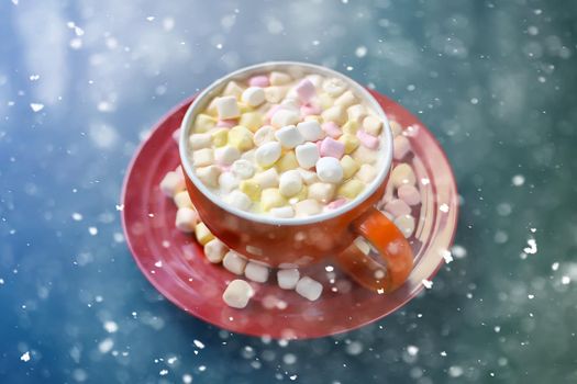 Cocoa drink with marshmallows in red ceramics cup. Snowfall effect.