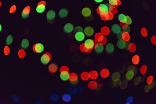 Colorful group of holiday lights on dark background in the night. Abstract backdrop