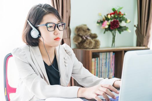 Teenage girl short hair in smart casual wear working on laptop while sit near window in home office