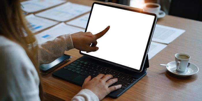 Mockup image of a black tablet with white blank screen on wooden desk.