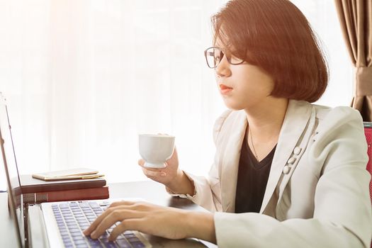 Woman teenage short hair in smart casual wear working on laptop while sit near window in home office