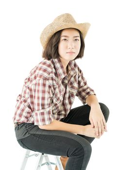 Young pretty woman in a cowboy hat and plaid shirt posing in studio with isolated on white background