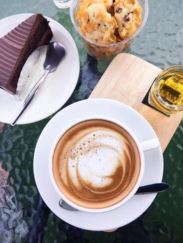 Hot coffee, cake chocolate and cookie on glass table at restaurant. top view.